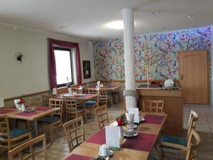 um restaurante com mesas e cadeiras e uma parede floral em Penzion Fantasy - restaurant em Lipník nad Becvou