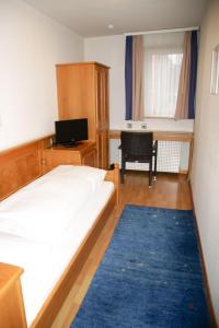 a bedroom with a bed and a desk and a television at Hotel Sonne in Lorch