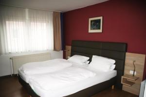 Hotel Sonne في لورخ: غرفة نوم بسريرين وجدار احمر