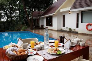 stół z jedzeniem obok basenu w obiekcie The IBNII - Eco Luxury Resort w mieście Madikeri