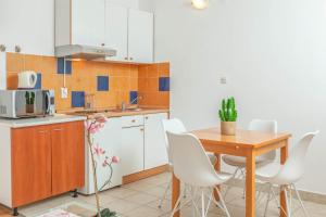 eine Küche mit einem Holztisch und weißen Stühlen in der Unterkunft Luka 2 in Podgora