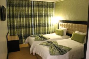 a hotel room with two beds with green pillows at Hotel Al Walid in Casablanca