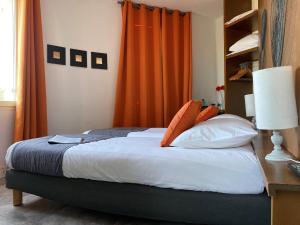 um quarto com uma cama com uma cortina laranja em Hôtel La Rotonde em La Croix-Valmer