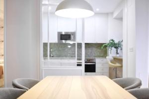cocina blanca con mesa de madera y sillas en Apartment Alaitz Rentería, en Rentería