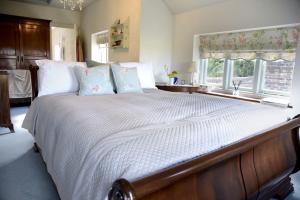 a bedroom with a large bed with white sheets and pillows at Spring Cottage in Amberley