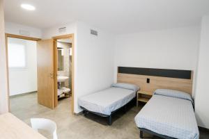 um quarto de hospital com duas camas e um lavatório em Pensión La Buena Vida em Caspe