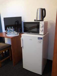 a microwave on top of a refrigerator next to a desk at Penzion Axa in Hradec Králové