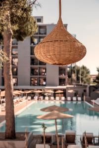 a straw umbrella and chairs and a swimming pool at Caramelo Palma Beach in Playa de Palma