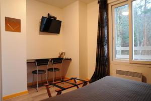a bedroom with a desk and a bed and a window at Hôtel du Lac in Treignac