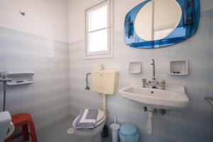een badkamer met een wastafel, een toilet en een spiegel bij GIAMAKI APARTMENTS in Sifnos