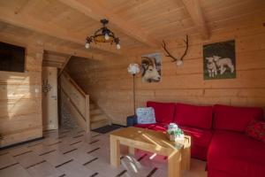 a living room with a red couch and a table at Całoroczne Domki Góralskie Kluszkowce-Czorsztyn in Kluszkowce