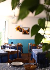 un comedor con mesas azules y una planta en Hotel Ornella, en Lido di Camaiore