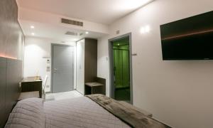 1 dormitorio con 1 cama y TV en la pared en BRIGANTE SUITES, en Misano Adriatico