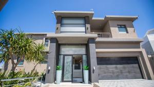 a house with glass doors and palm trees at C' la Vie Luxury Accommodation in Melkbosstrand