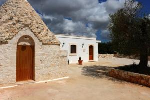 a white building with a door in a yard at Agriturismo L'Aire Alberobello in Alberobello