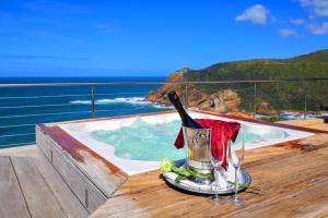 a hot tub with a bottle of wine sitting on a deck at Alexander Guest House in Knysna