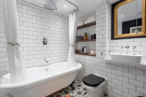 a bathroom with a tub and a toilet and a sink at Chapel Loft in London