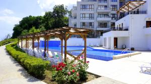 a pool with chairs and a pavilion next to a building at Апартаменти Бяла Клиф - Byala Cliff Apartments in Byala