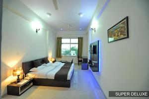 a bedroom with a king sized bed and a television at Hotel Shivam in Ajmer