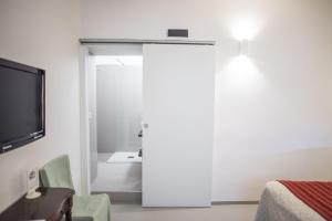um quarto com uma porta com uma televisão e uma cama em Aretusa Vacanze B&B em Siracusa