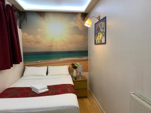 a bedroom with a bed and a painting of the beach at Barking Hotel in Barking