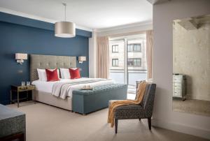 a bedroom with a bed with red pillows and a chair at Arlington House Apartments in London