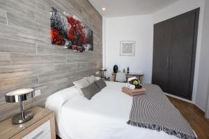 a bedroom with a white bed and a wall at Hostal Casa Mercedes in Nerja