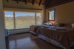 a bedroom with two beds and a large window at Hostería La Chira in San Martín de los Andes