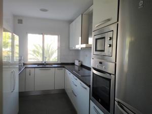 マラガにあるEspectacular Apartamento Malaga Playa Y Piscinaのキッチン(白いキャビネット、ステンレス製の電化製品付)