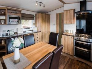 a kitchen with a wooden table and chairs and a kitchen with a stove at Cairn View Chalet in Aviemore
