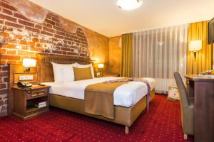 a hotel room with a bed and a brick wall at Romantik Hotel Scheelehof Stralsund in Stralsund