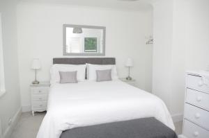a white bedroom with a large white bed and a mirror at Windy Willums in Christchurch