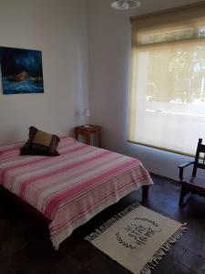 1 dormitorio con cama, ventana y silla en GLAMAUÉ en Carhué