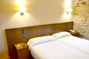 a hotel room with two beds and a lamp at Hotel Alda Avenida in Santiago de Compostela