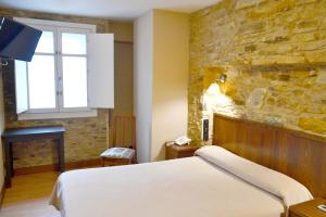 sypialnia z łóżkiem i kamienną ścianą w obiekcie Hotel Alda Avenida w Santiago de Compostela