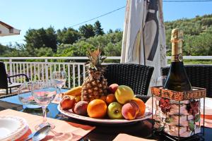 a plate of fruit on a table with a bottle of wine at Apartment Maja's Style in Vela Luka