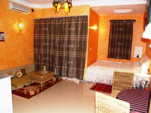 a bedroom with a bed and a table and curtains at Dar El Amen Appartements in Mahdia