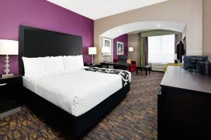 um quarto de hotel com uma cama grande e paredes roxas em La Quinta by Wyndham Jourdanton - Pleasanton em Jourdanton