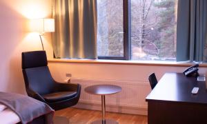 Habitación de hotel con escritorio, silla y ventana en Hotel Montebello en Oslo