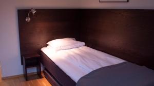 Cama pequeña con cabecero de madera y sábanas blancas en Hotel Montebello, en Oslo