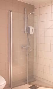 una doccia con porta in vetro in bagno di Hotel Montebello a Oslo