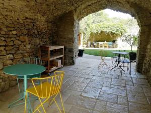 a patio with tables and chairs in a stone wall at Le Mas Bellane in Salettes