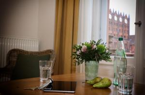 
a table with a glass of water and a vase of flowers at Aparthotel Markt Fuffzehn in Stralsund
