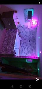 Habitación con 2 filas de sillas y luces púrpuras en Le Menhir Jacuzzi Lit 200x200 en Le Cendre