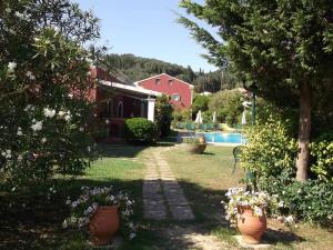 a garden with flowers and a house and a swimming pool at Villa De Loulia in Peroulades