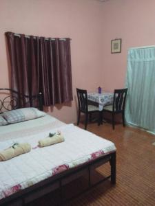 1 dormitorio con 2 camas y mesa con sillas en ห้องพัก โฮมทรัพย์ en Ban Thung Pla Kat