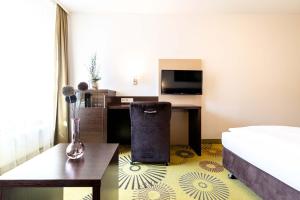 a hotel room with a bed and a desk and a television at Altstadthotel Guesthouse Die Galerie in Ingolstadt