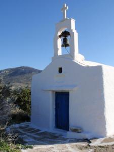 a small white church with a blue door and a bell at Kalados -Beachfront Studios & Restaurant - in Kalando