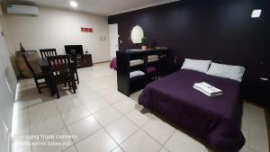 1 dormitorio con cama morada, mesa y sillas en Departamentos "Oli", en Mendoza