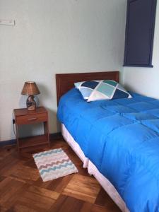 a bedroom with a blue bed and a night stand with a lamp at Viña Colores in Viña del Mar
